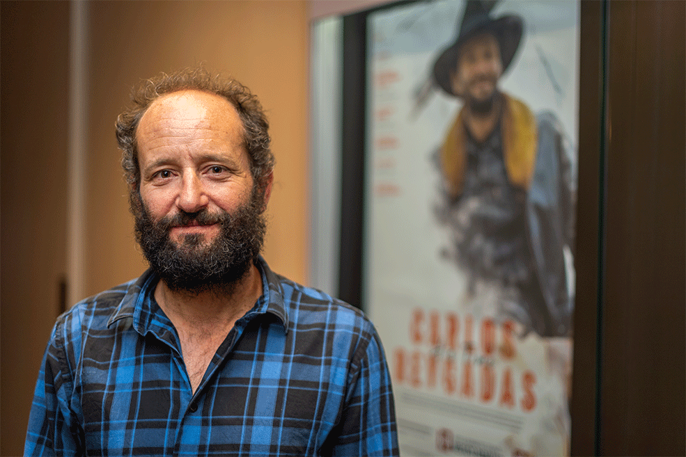 卡洛斯·雷加达斯(Carlos Reygadas)在IU电影院大厅的乔根森电影制作人之旅的海报前摆姿势。