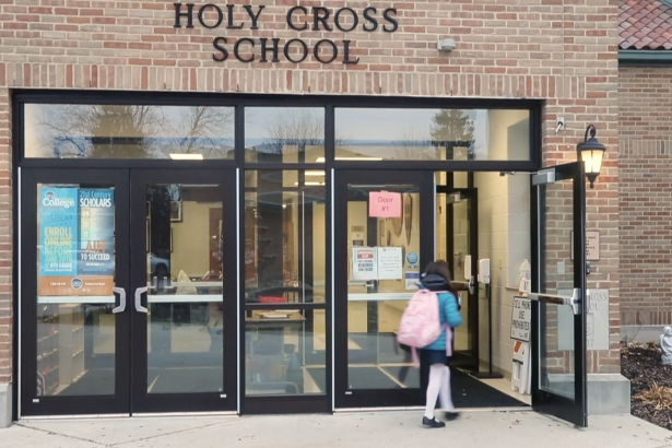 学校外的圣十字。一个孩子进入大楼。