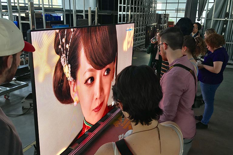 人站在屏幕上显示一个女人在中国传统服饰在学生表演。