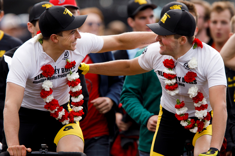 两个戴着棒球帽和帽子的男人微笑着互相碰碰肩膀