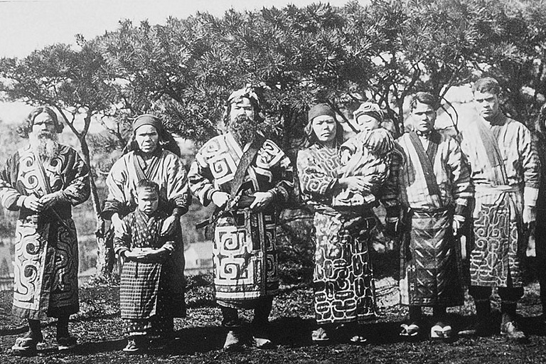 八阿伊努人的成人和儿童穿着传统服装站在一排面对镜头。